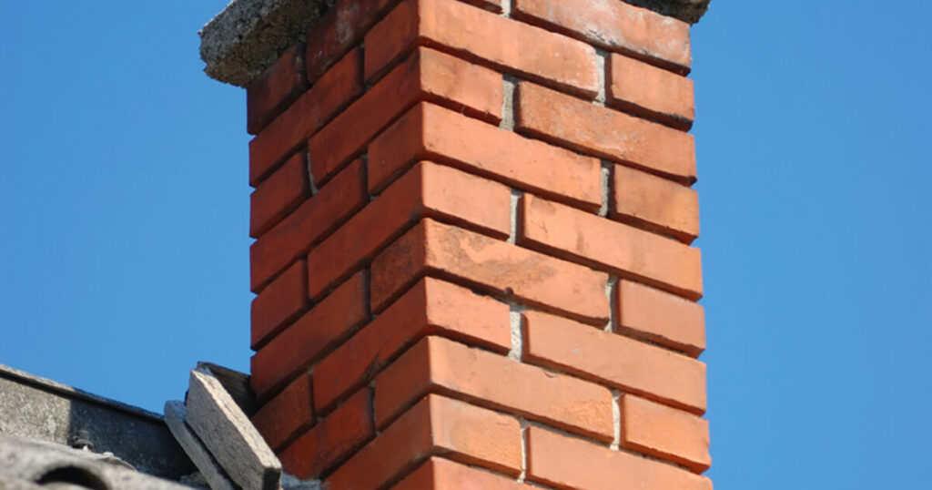 Brick chimney with concrete cap and clay flue inspected from the roofline